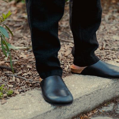 A pair of black mules standing on a curb.