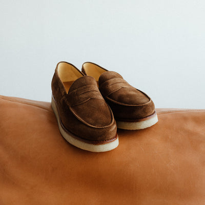 A pair of brown loafers on a leather couch.