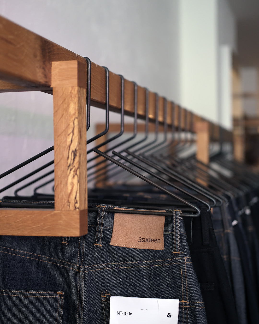 A photo of jeans hanging on a wooden bar