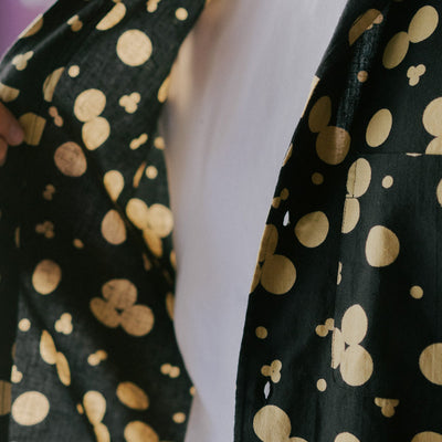 A close up image of a black shirt with a cream pattern printed on.