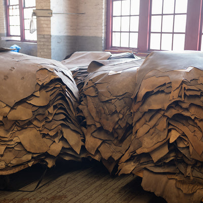 Piles of untanned horsehide sit in a factory awaiting colors to be applied.