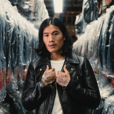 A man in a black leather jacket stands in a sea of plastic bagged jackets.