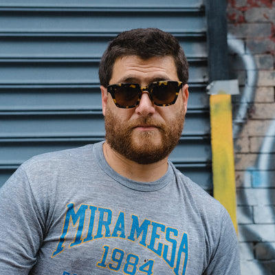 A portrait of a man in a grey tee and sunglasses 