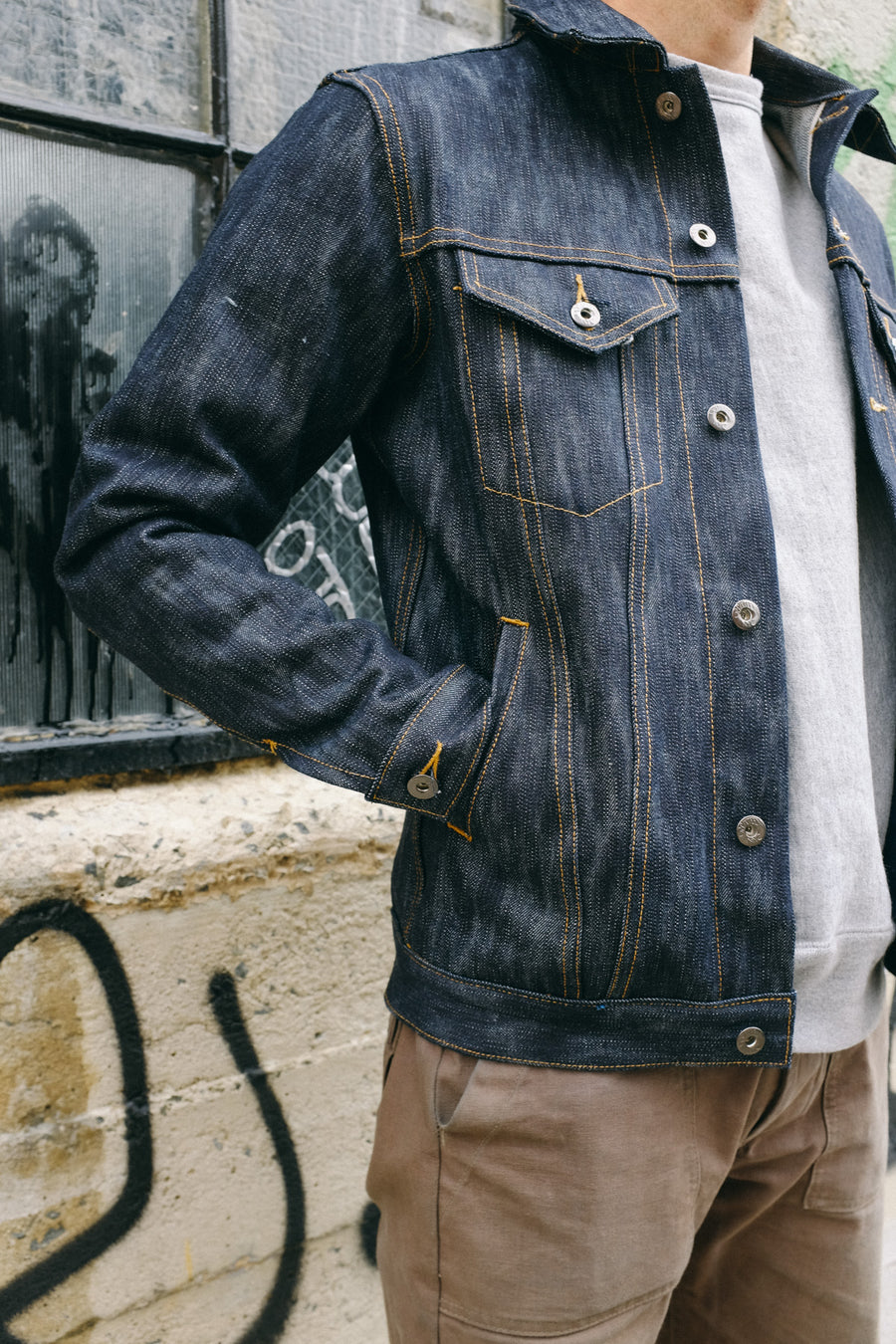 The model has his hands in the inset pocket of the 3sixteen Type 3s jacket.