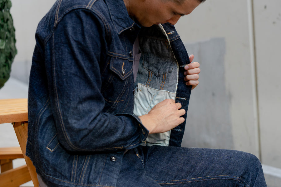 The model reaches into the inside of his jacket and shows the selvedge detailing inside the placket.