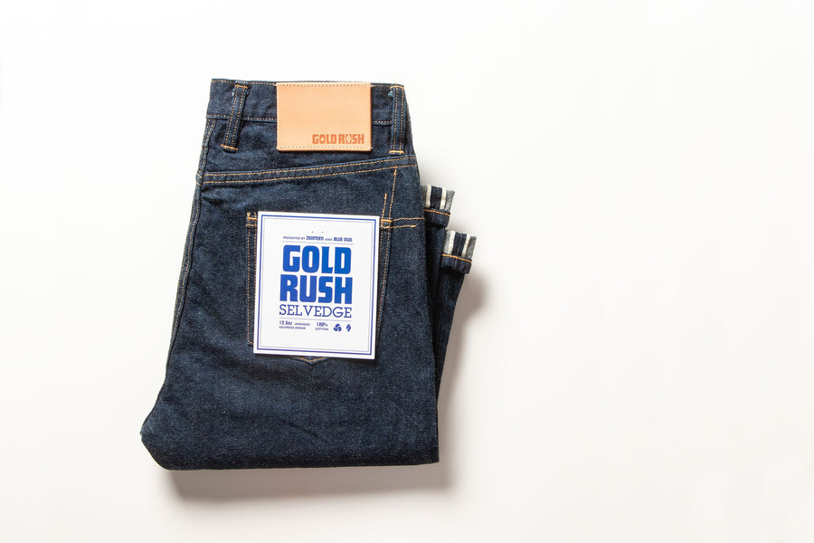 A pair of folded jeans on a white background showing the pocket flasher.