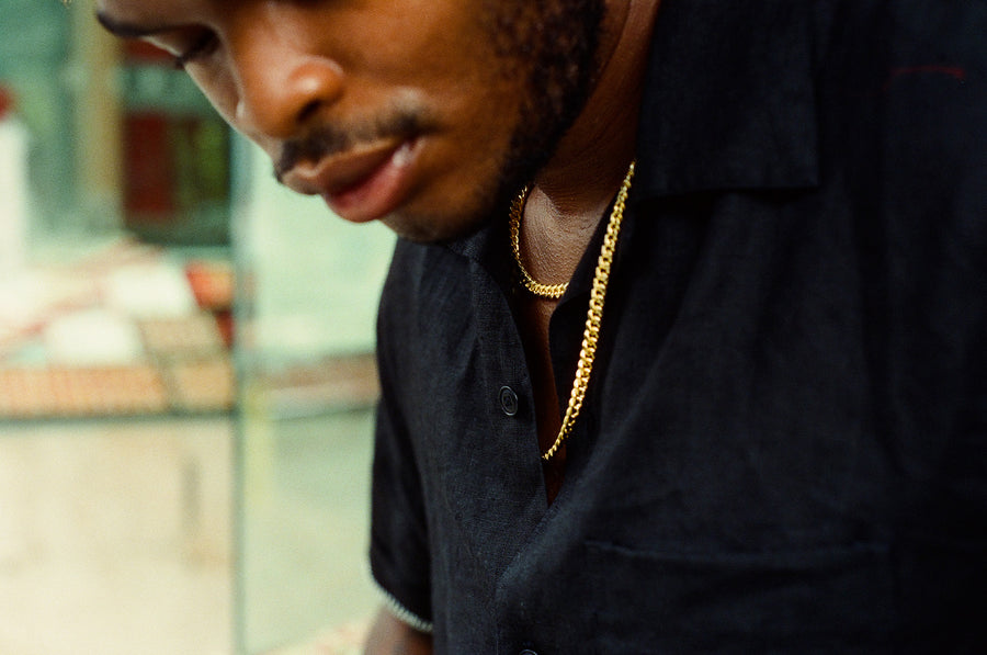 A closeup shot of a gold chain under a black shirt.