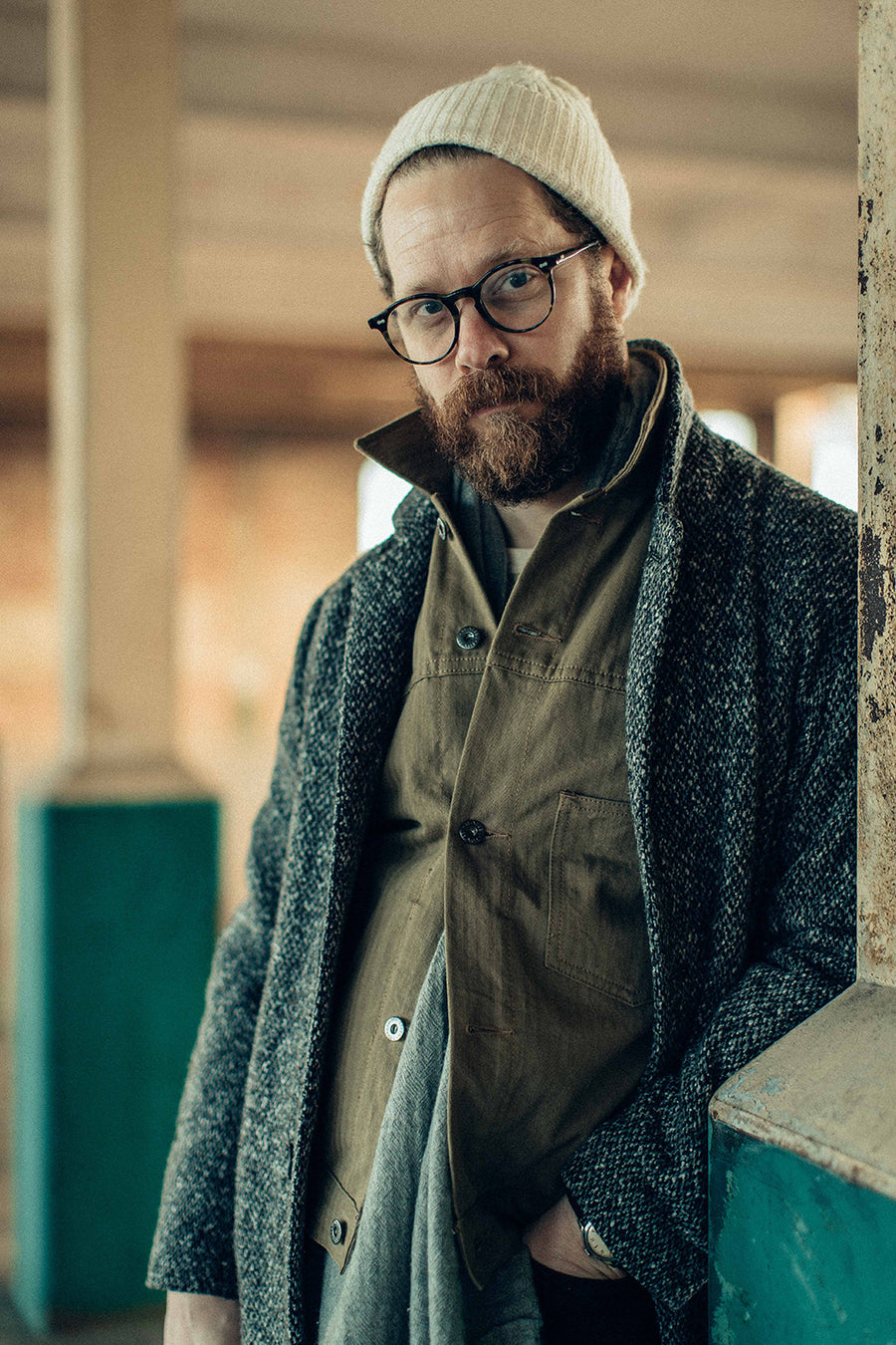 A portrait of a bearded man in a wool coat and tan jacket.