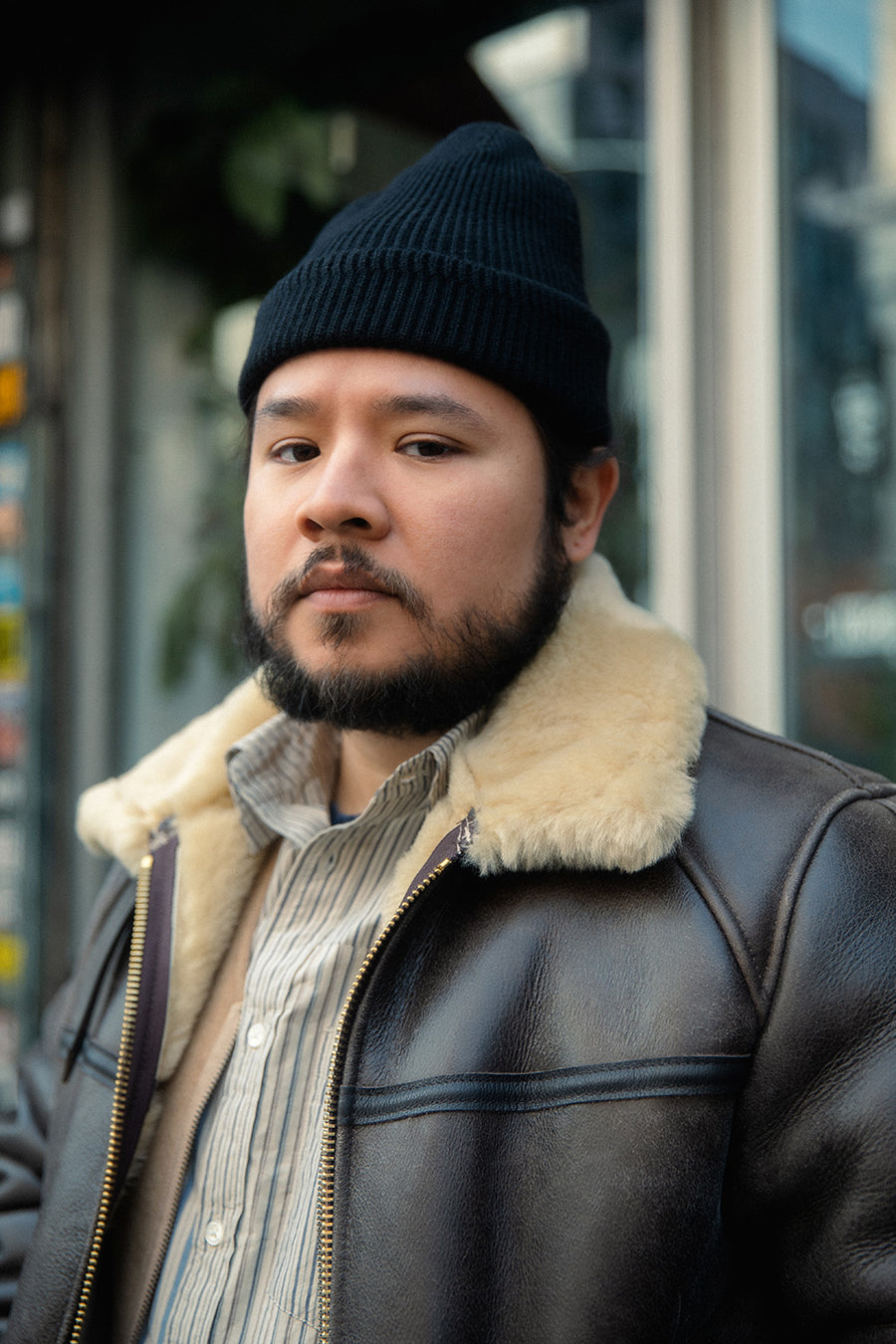 A portrait of a man wearing a shearling leather jacket and black beanie.