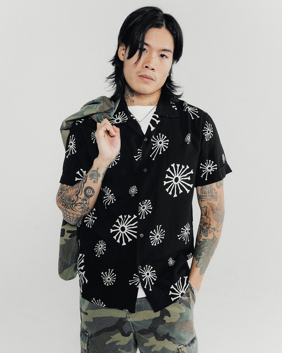 A man poses in a black shirt and camo pants.