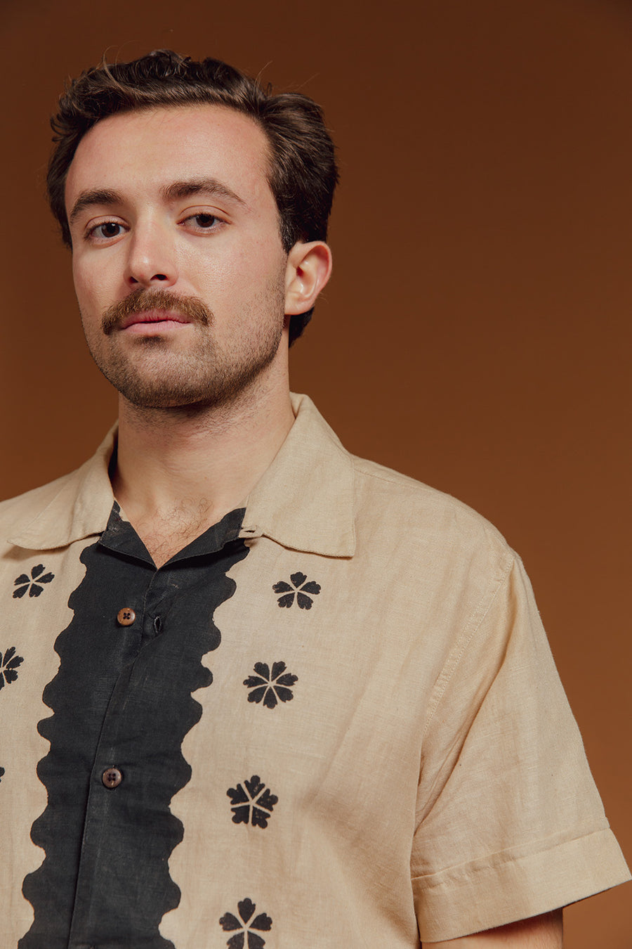 A man wears the finished studio floral shirt against an amber backdrop.