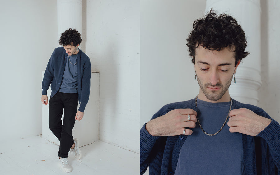 A man wearing a blue tee and cardigan leans over to the right.