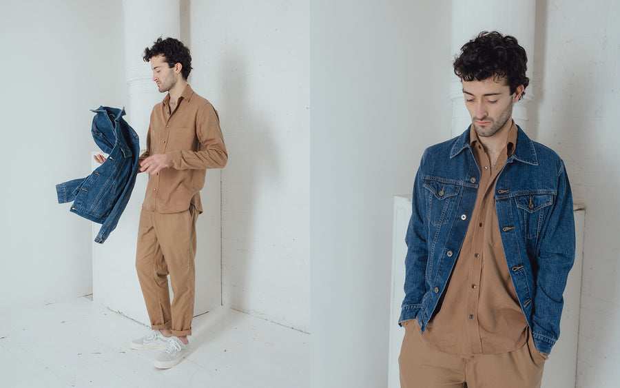 A man casually tosses a blue denim jacket in the air.