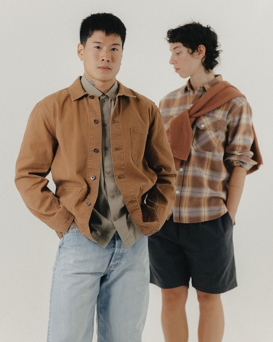 A man and woman in rust colored jackets and shirts pose for the camera.