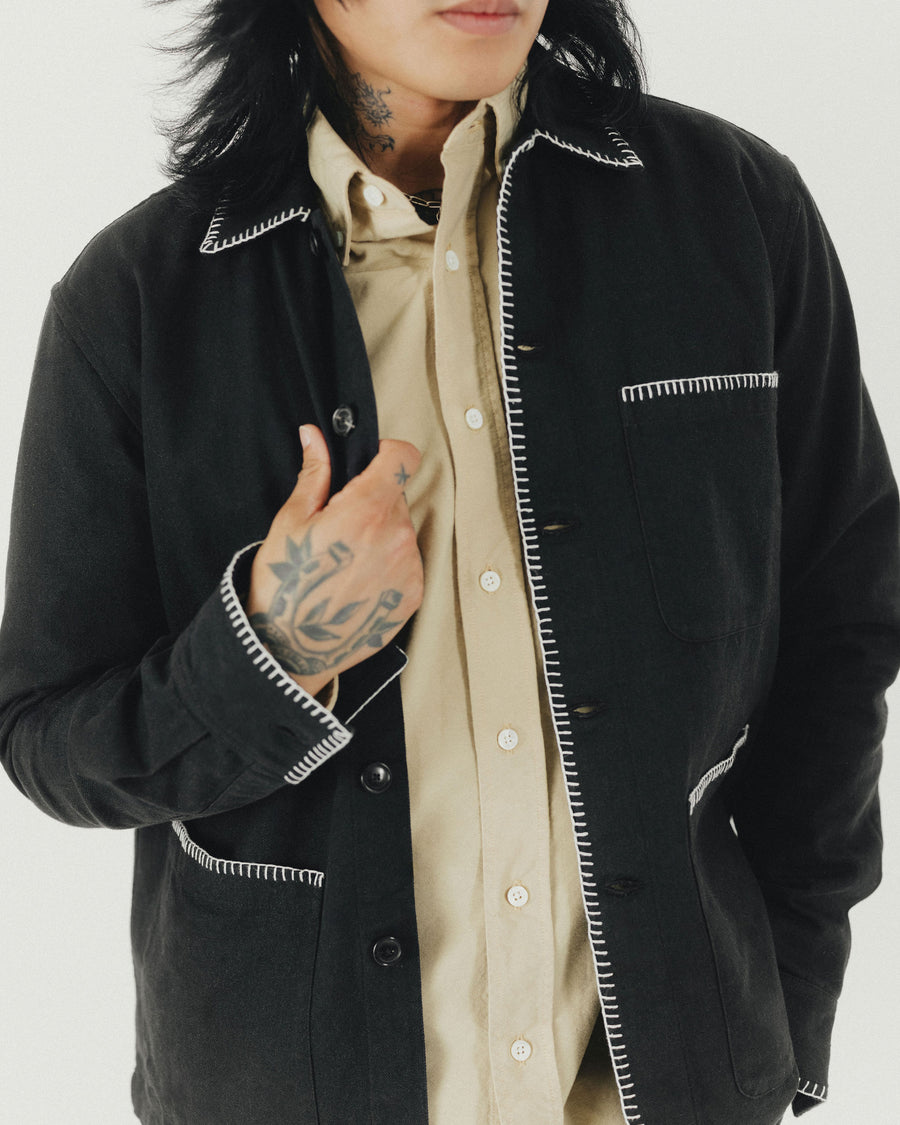 A detail shot of a man in a tan shirt with a black jacket.