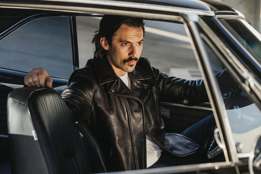 Model wearing a leather jacket inside of a car.