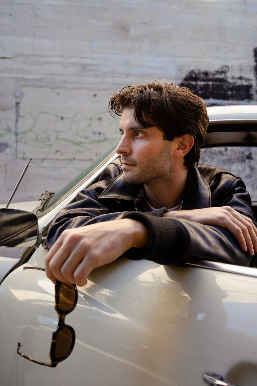 A man leans out the window of his car with the jacket on.