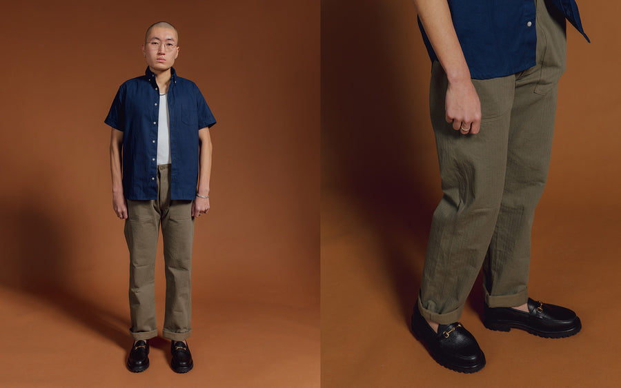 A man in a blue short sleeve shirt and olive pants.