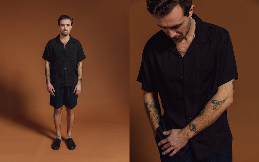 A man in a black shirt and navy shorts.