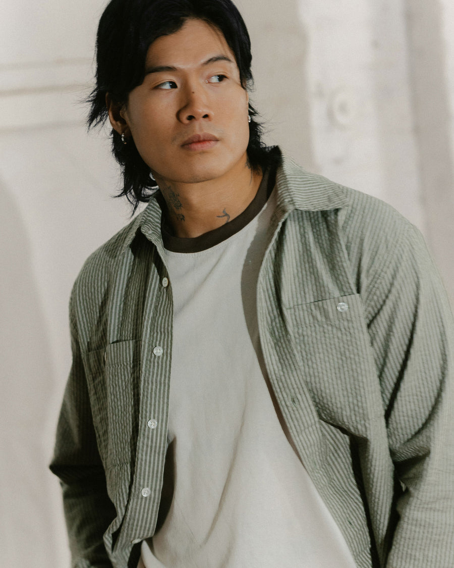 A slightly blurry picture of a man in an olive striped shirt.