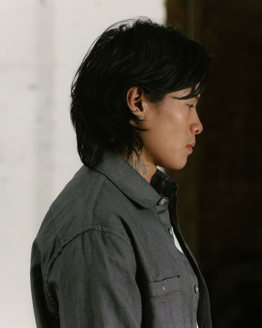 A side profile of a man in a charcoal shirt.