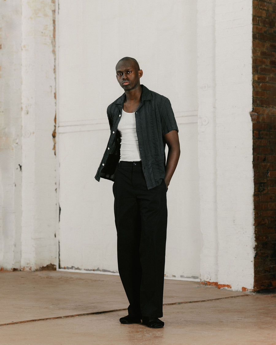 A man in a black short sleeve shirt over a tank top.
