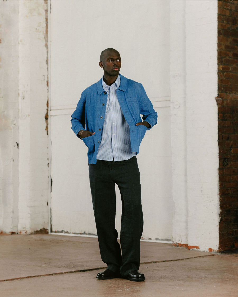 A man in a sky blue jacket and dark pants poses.