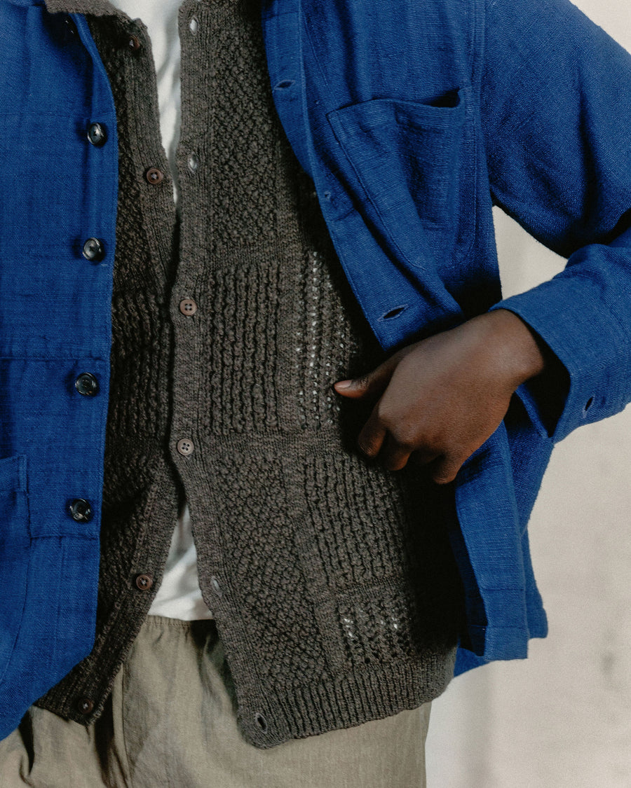 A close up detail shot of a blue jacket layered over a textured brown knit shirt.