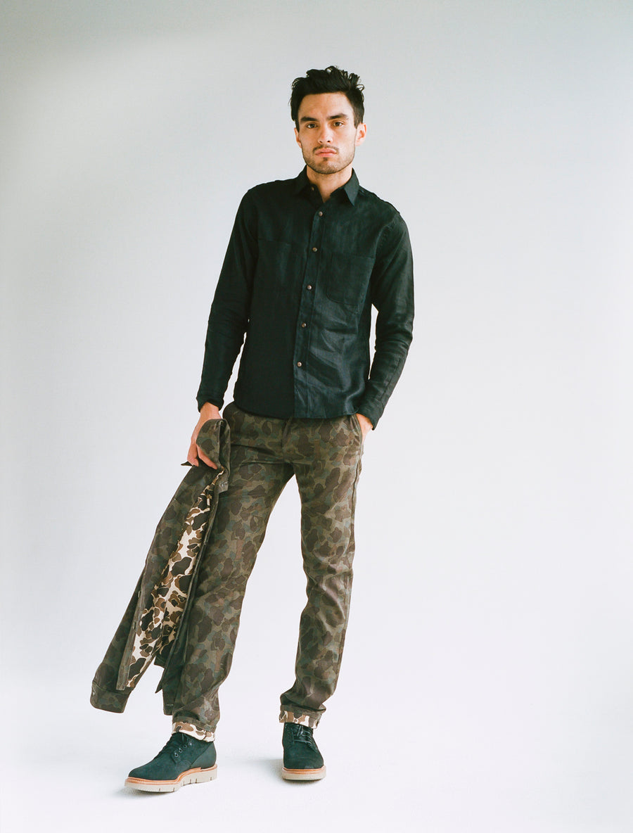 Model wears a black linen shirt with camoflauge pants.