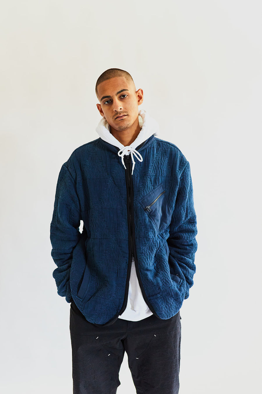 A young man wearing the jacket looks into the camera intently.