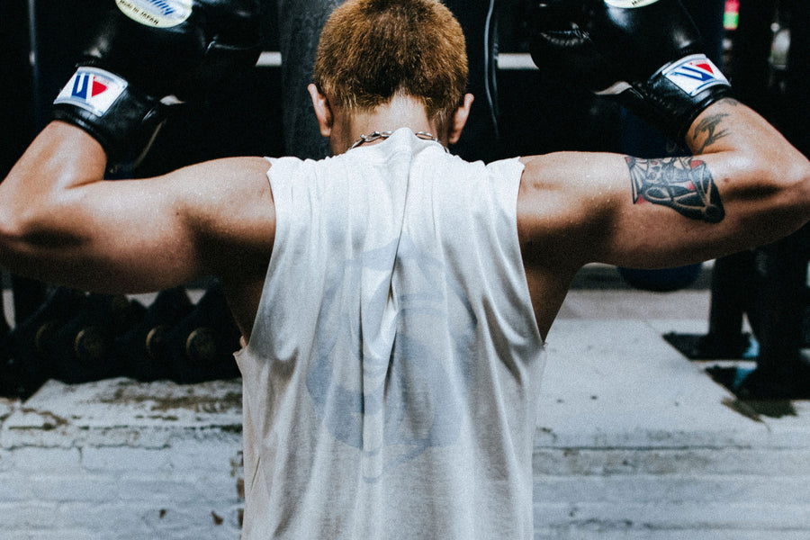 A man flexes his muscles and shows the back of his t-shirt.