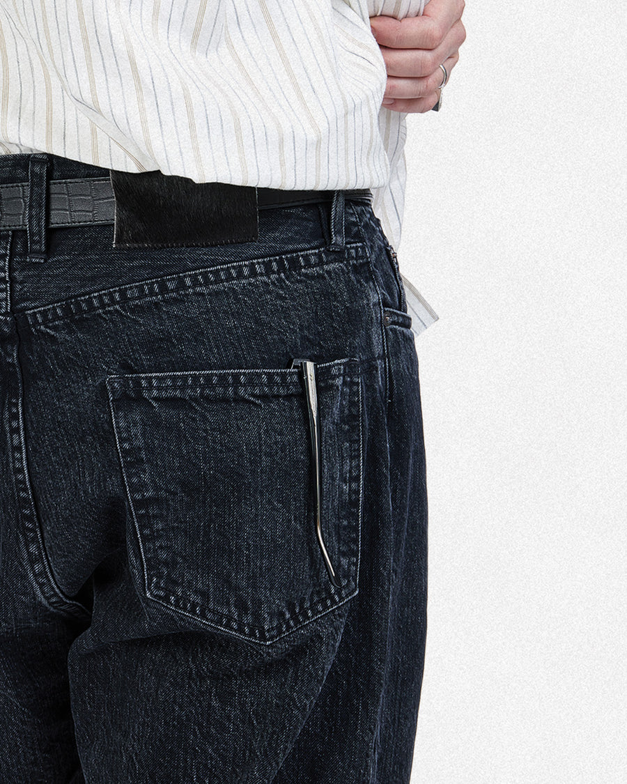 A black jean with a black hairy leather patch and glasses in the back pocket.