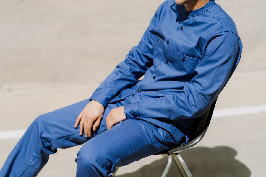 A close up shot of a man in a french blue shirt and work pants.