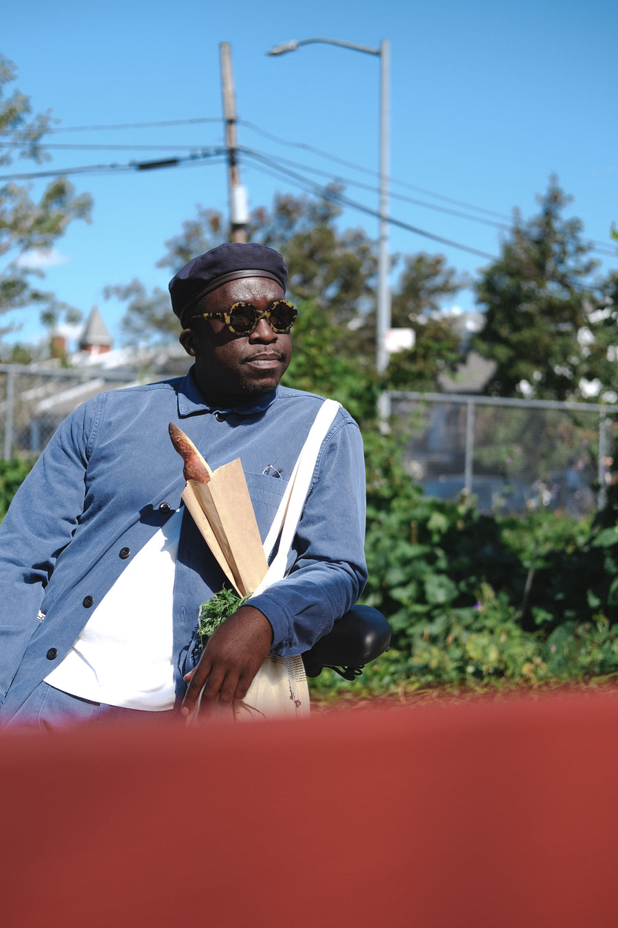 A man in the blue full suit and sunglasses stands in a green garden.