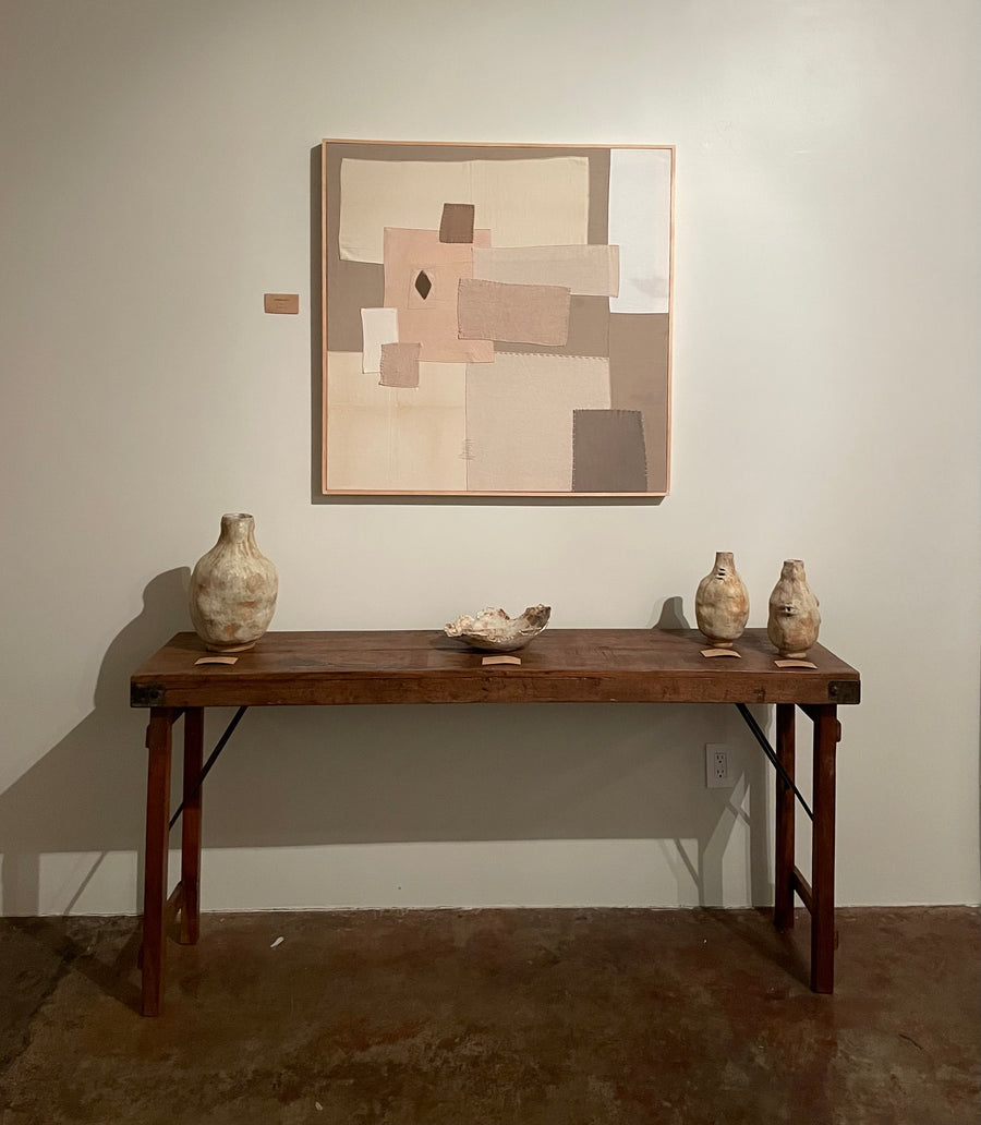 Art and ceramics on a table against a white wall.