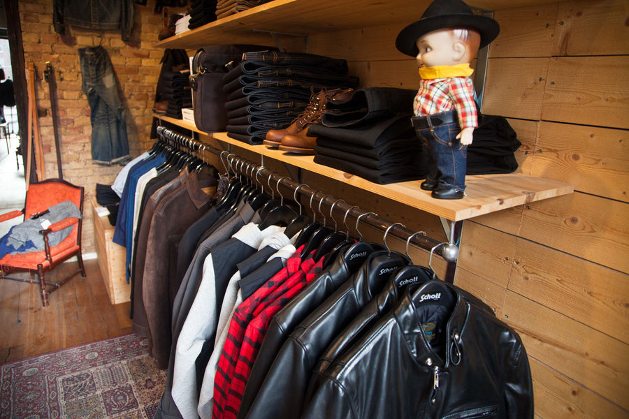 Closeup shot of an iron clothing rack inside Meadow, with leather jackets and knits hanging.