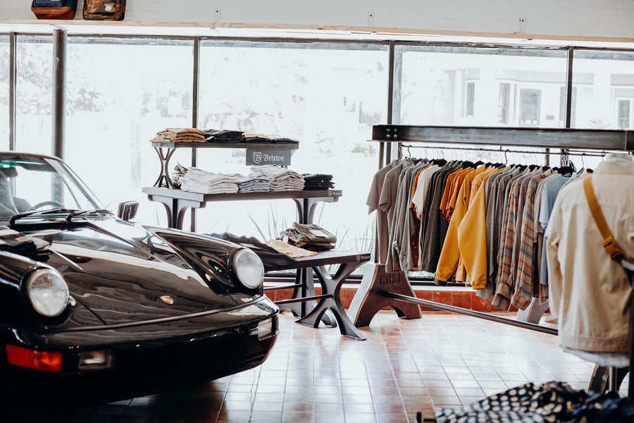 A view of the shop floor at Iron Shop Provisions with a vintage Porsche on the left and a rack of clothes on the right.