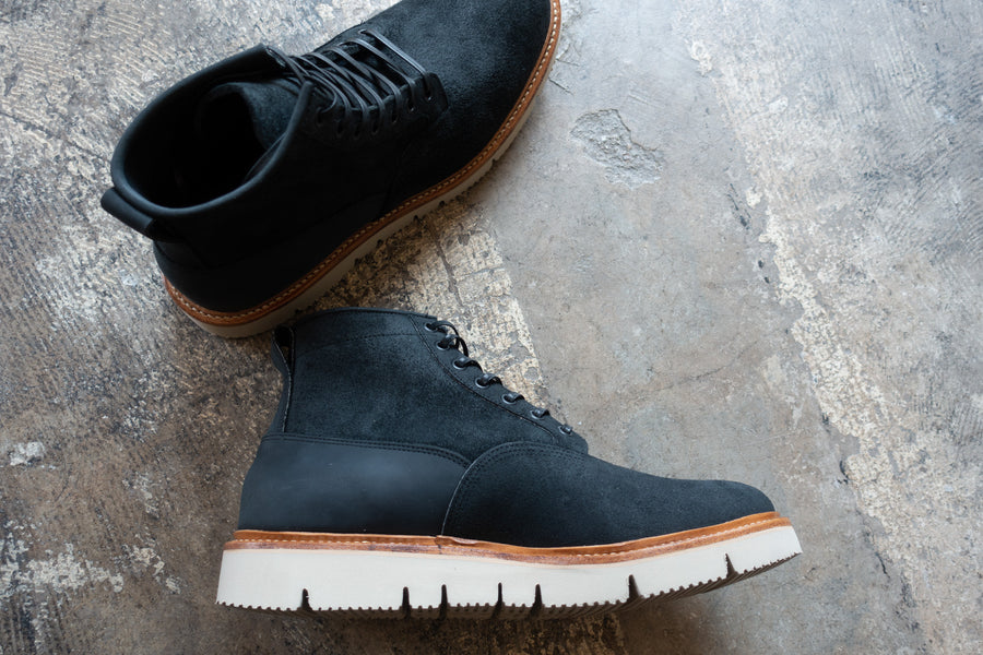 A pair of black Scout boots on the concrete floor.