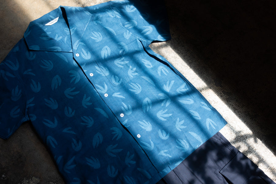 A blue shirt lays flat on a floor.