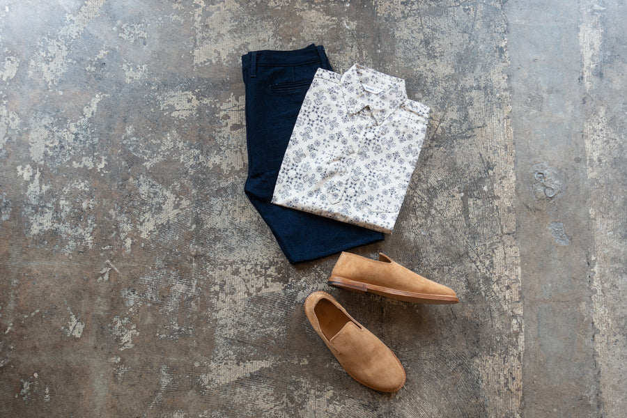 A flatlay of a popover, shorts and slippers.
