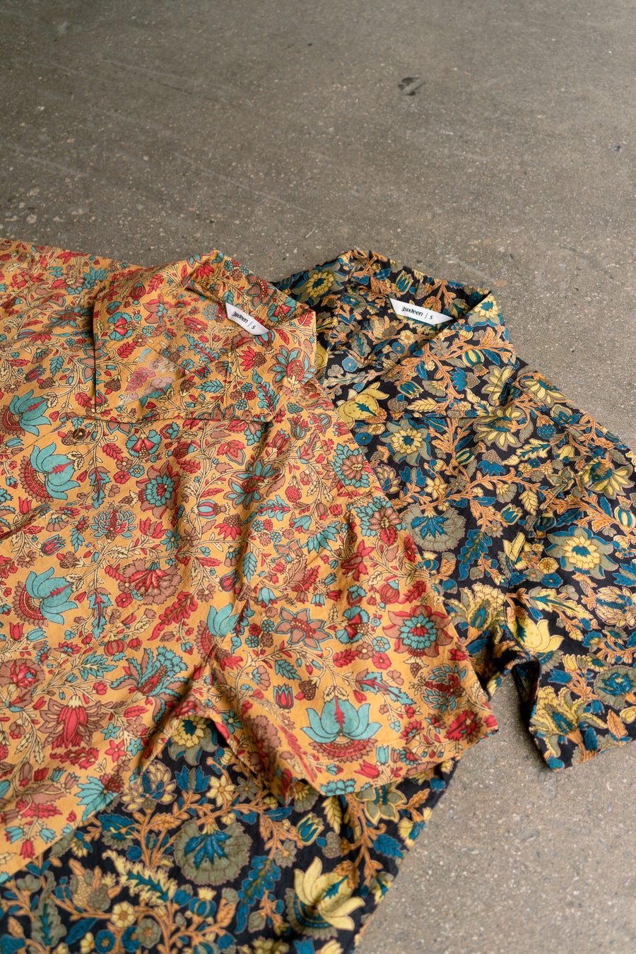 Two floral shirts showcasing beautifully printed fabric lay on a floor.