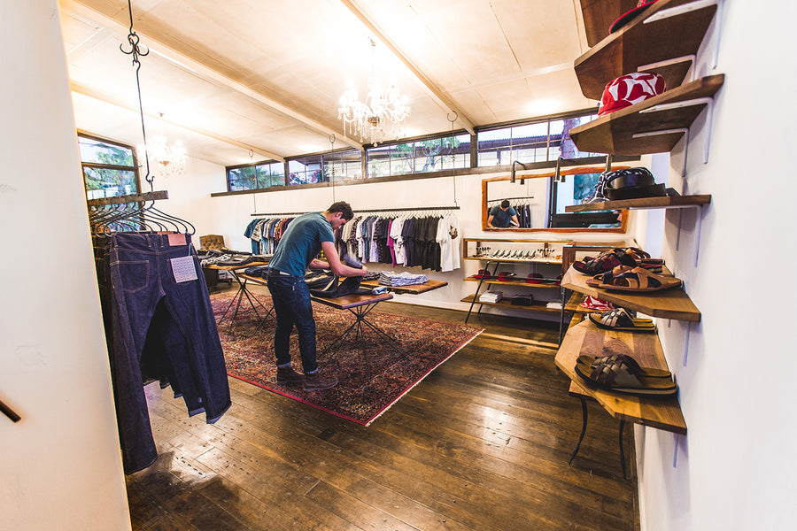 Man folding jeans on a display table.
