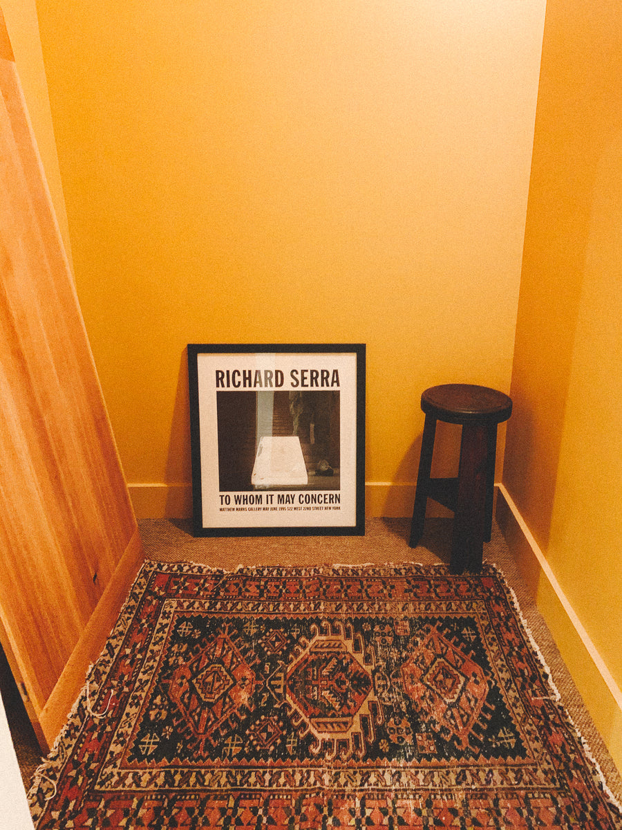 A golden yellow room with a rug and a stool.