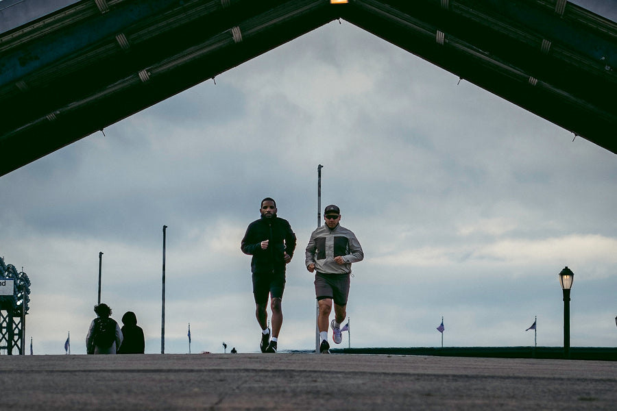 Two men run down a ramp in workout clothing.