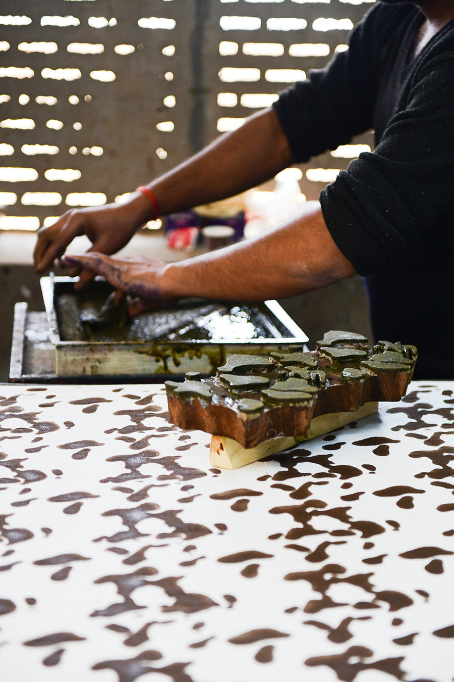 Wood blocks are being dipped into ink before being stamped onto the fabric.