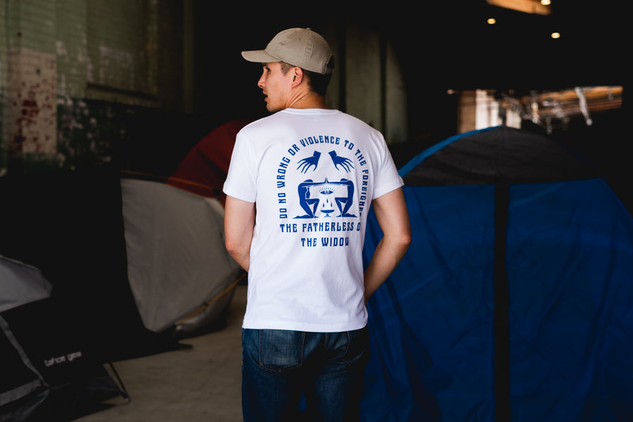 A young man in a white t-shirt with graphic print on the back walks away.