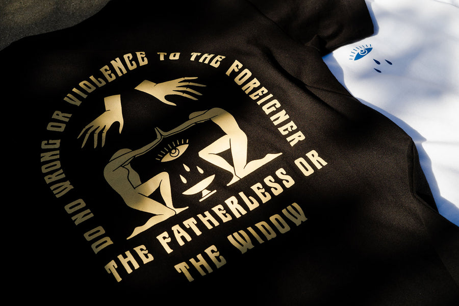 Two graphic tees lay artfully on the floor as sunlight pours onto them.