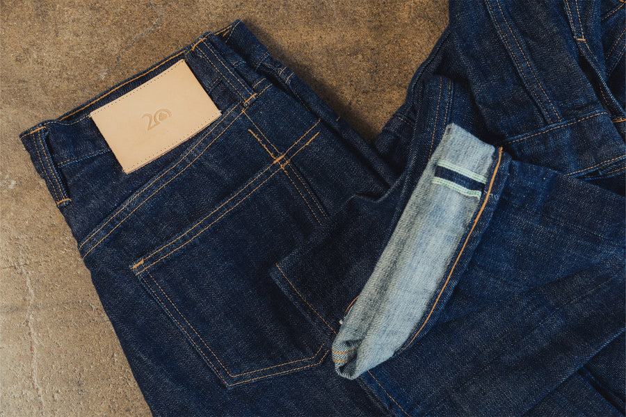 A pair of dark denim on the floor with a tan leather patch.