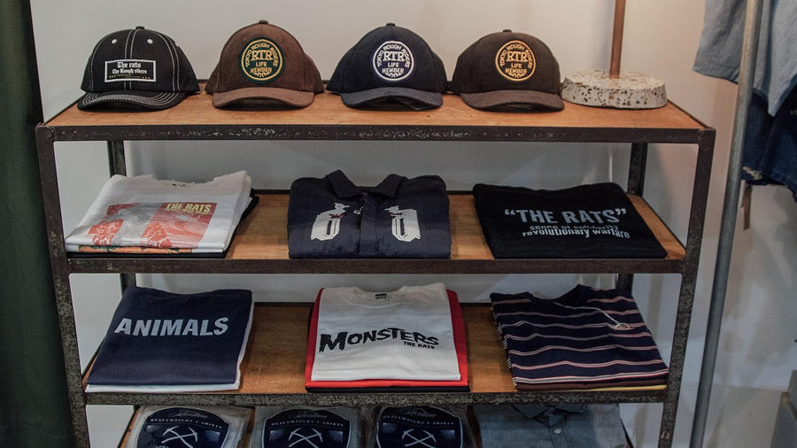 Shirts and hats on display shelf.