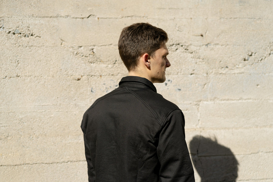 A man faces away from the camera in a black shirt.